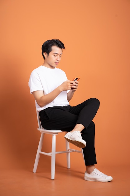 Man sitting on chair isolated on orange background