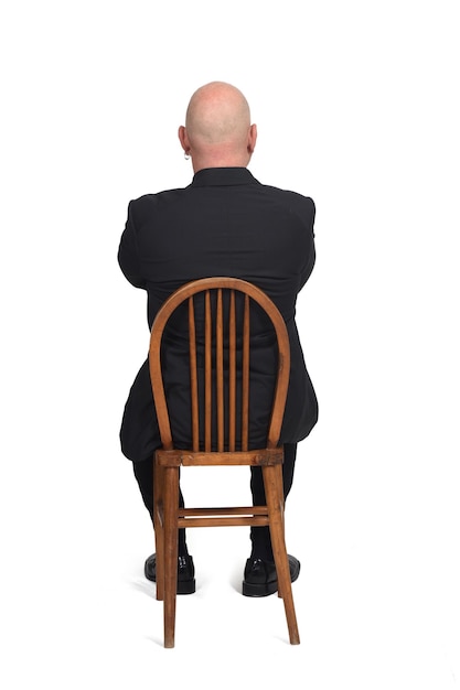 Мужчина сидит на стуле спиной на белом фоне,