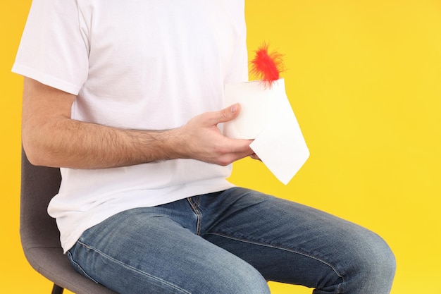 Photo man sitting on chair on yellow background. hemorrhoids concept