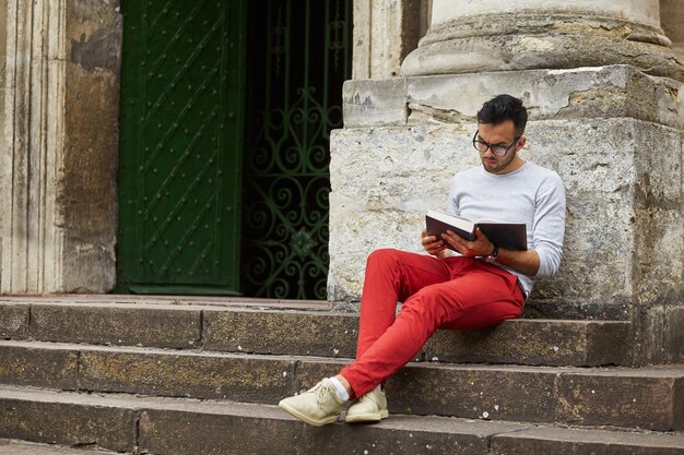 Man sitting on city steps reading book