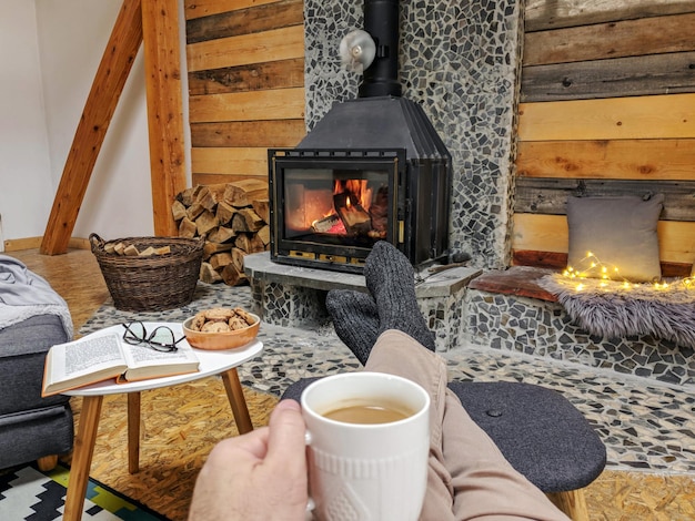 Man sitting comfortably with a cup of coffee relaxing at the fireplace on a winter evening