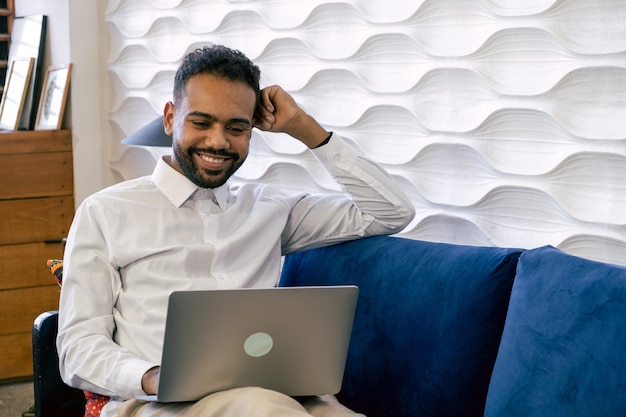 Man sitting on couch in living room with laptop and credit card