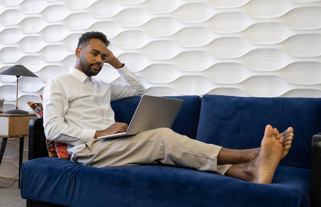 Man sitting on couch in living room with laptop and credit card