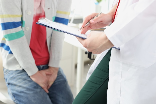 Man sitting at doctor appointment and holding on to genital area closeup