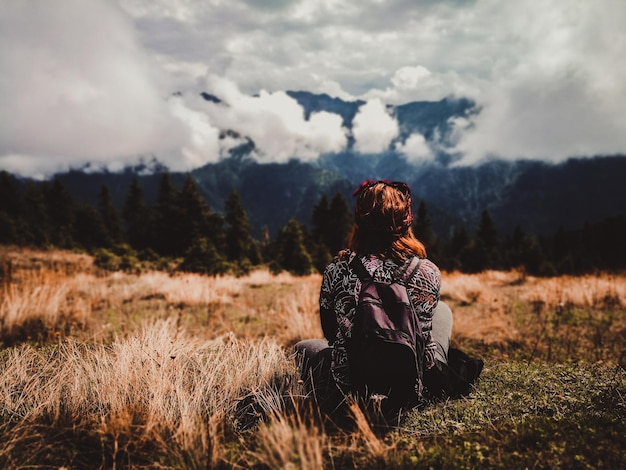 Photo man sitting on field against sky