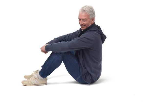 Man sitting on the floor with legs folded and looking at camera on white background