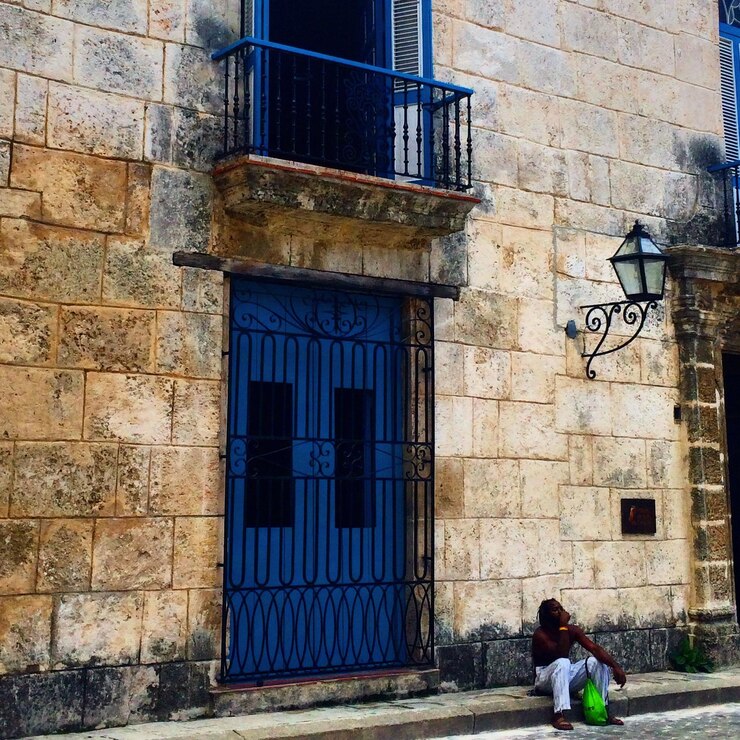 फोटो man sitting on footpath against building
