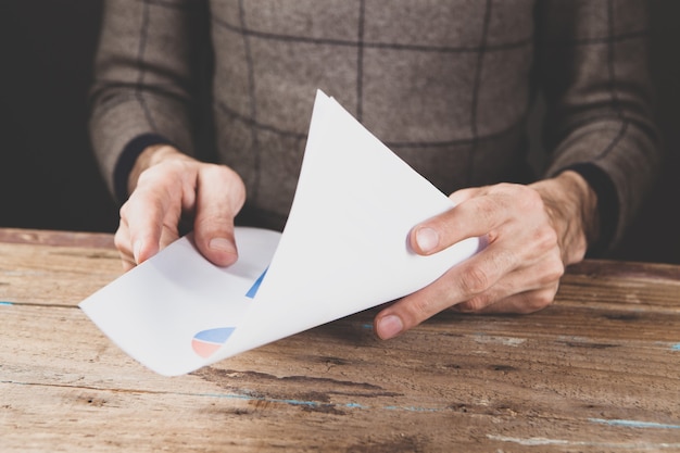 A man sitting in front of a table holding a paper