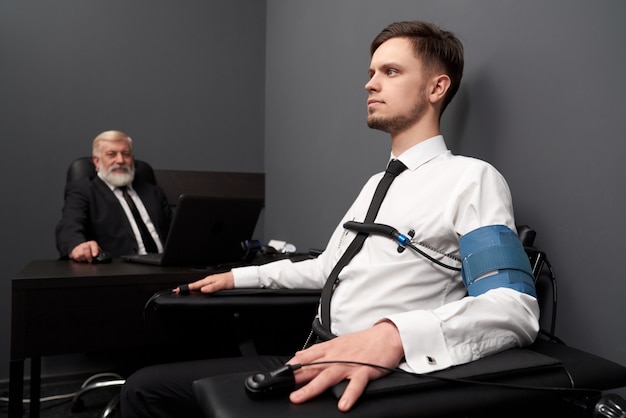 Man sitting in grey room and checking with polygraph.