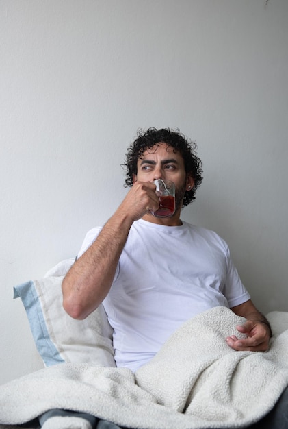 man sitting on his bed drinking hot tea