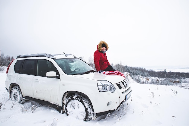 Man sitting on the hood of the suv car with flag of usa car travel concept