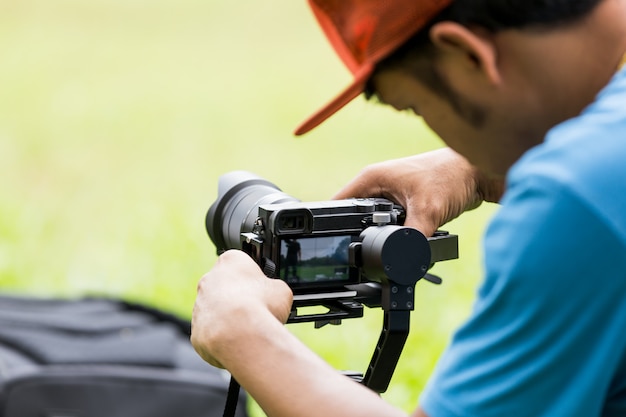 写真 カメラの安定化モノポッドジンバルを設定して公園に座っている男