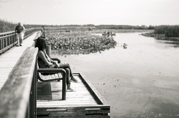 Photo man sitting on jetty by pier on lake