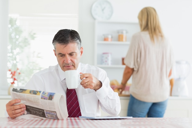 Man sitting at the kitchen table while reading a newspaper