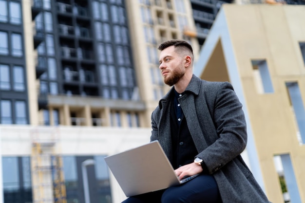 A man sitting on a ledge using a laptop