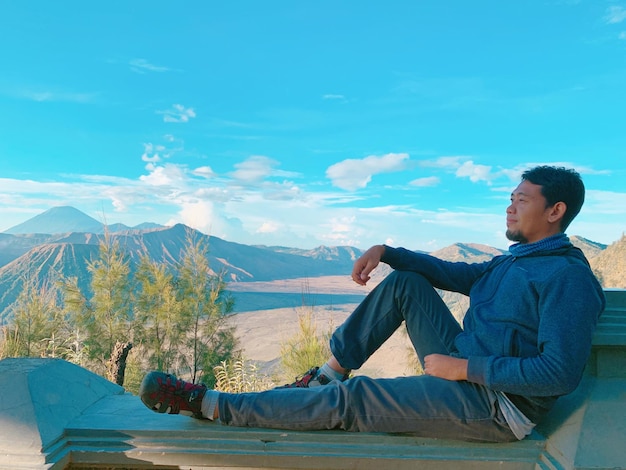 Foto uomo seduto sulla montagna a guardare la vista