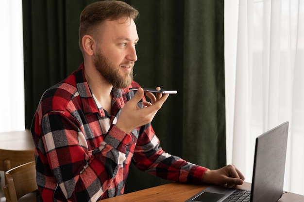 Foto uomo seduto in ufficio che parla su altoparlante che fa riconoscimento vocale usando i servizi internet attraverso l'assistente virtuale che registra l'app traduttore di messaggi audio