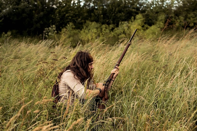 写真 野原の草の上に座ってプロップ銃を握っている男