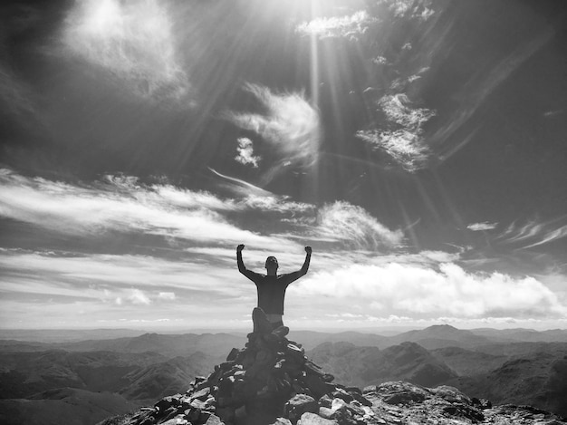 写真 空の向こうの山頂に座っている男