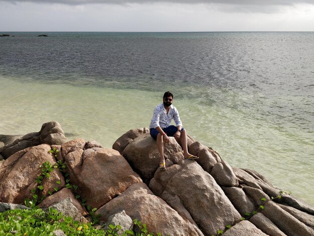 写真 海辺の岩の上に座っている男