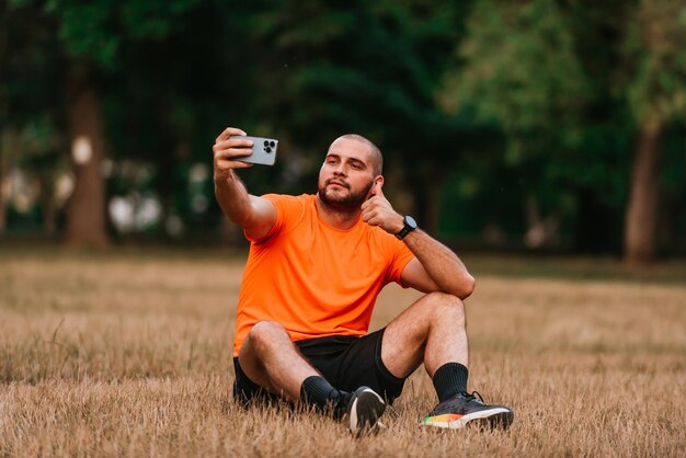 A man sitting in park and making a selfie after finishing his morning training