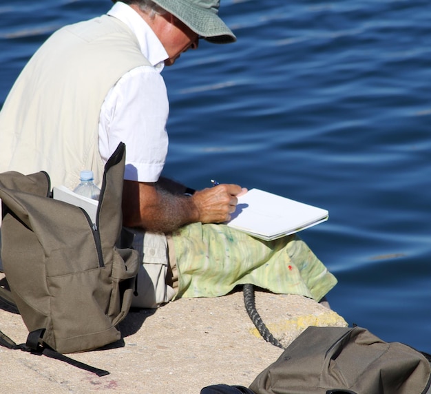 Man sitting on pier drawing