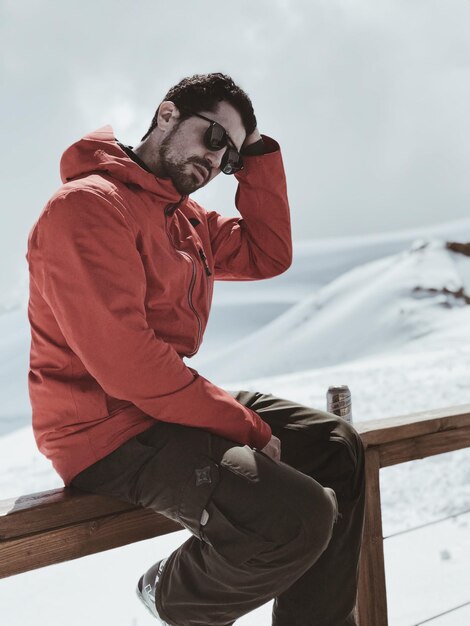 Photo man sitting on railing against snow covered landscape