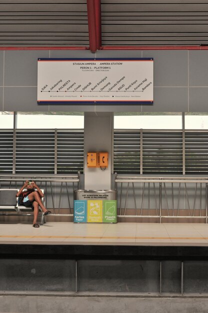 Foto uomo seduto alla stazione ferroviaria