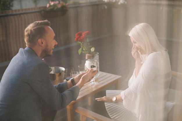 Foto equipaggi la seduta nel ristorante che dà l'anello di fidanzamento alla sua amica