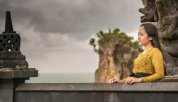 Photo man sitting on retaining wall against sky