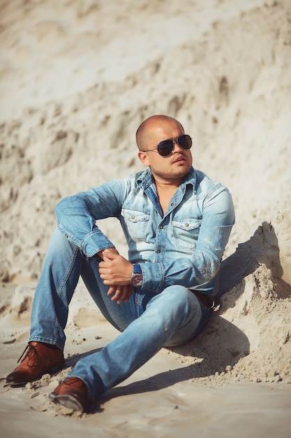 Man sitting on the sand in glasses