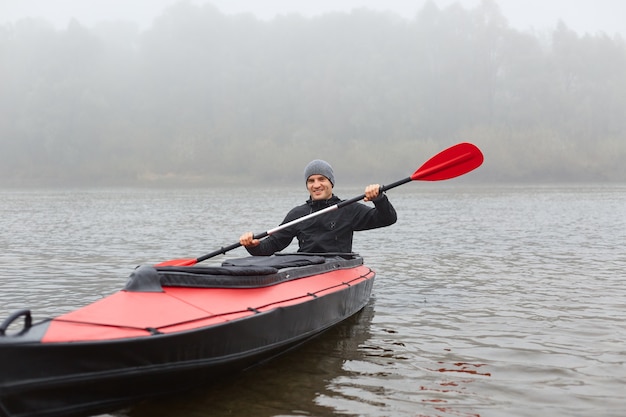 Man sitting smiling in kayak and holding paddle in hands