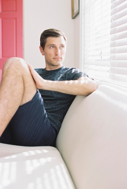 Man sitting on a sofa by a window relaxing