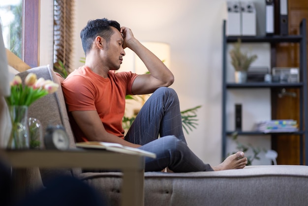 A man sitting on a sofa at home is sad disappointed and upset