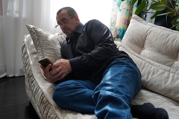 man sitting on sofa and looking at smartphone