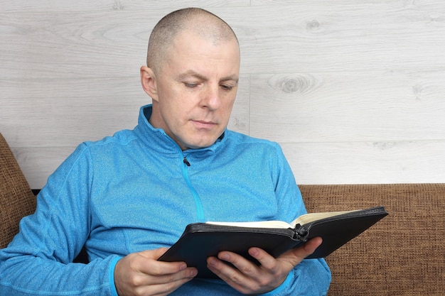 Man sitting on sofa and reading a book of the Bible