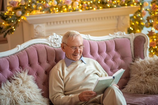 man sitting on a sofa reading a book