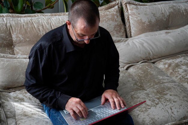 man sitting on sofa and working on laptop