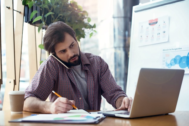 Uomo seduto al tavolo in un ufficio creativo ed elegante che lavora occupato