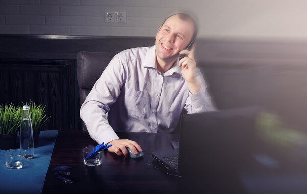человек сидит за столом и работает на ноутбуке