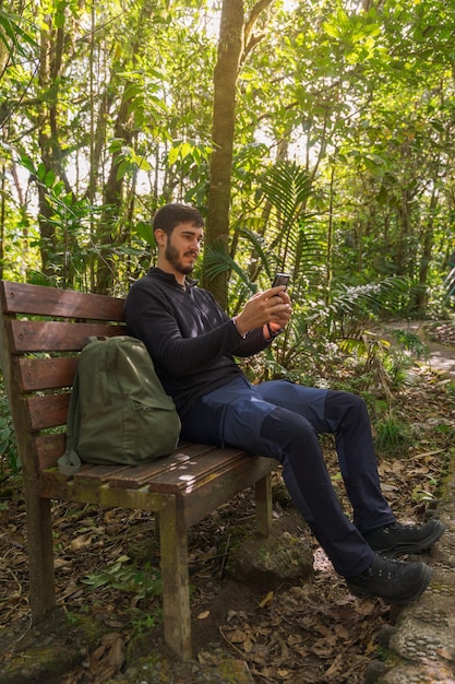 Foto uomo seduto utilizzando il telefono cellulare in natura