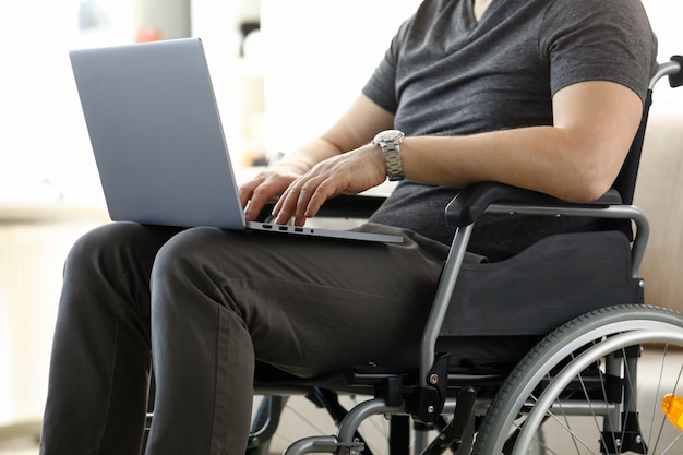 Man sitting in wheelchair working with laptop computer