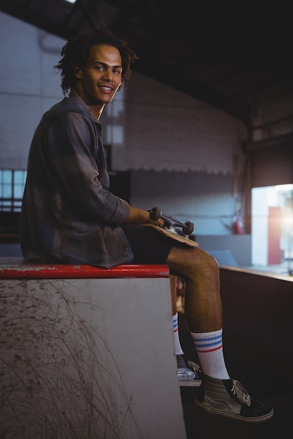 Man sitting while holding skateboard