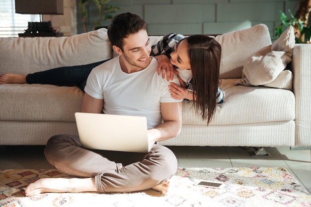 Man sitting with laptop and his woman at home