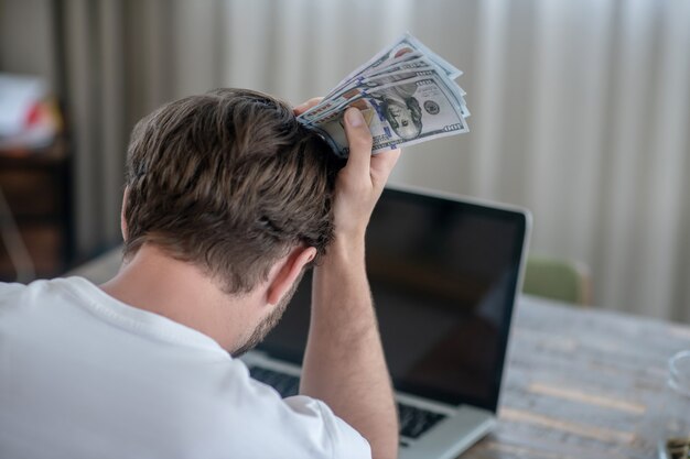 手にお金を持って座って動揺している男