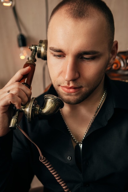 Uomo seduto con telefono in metallo vintage