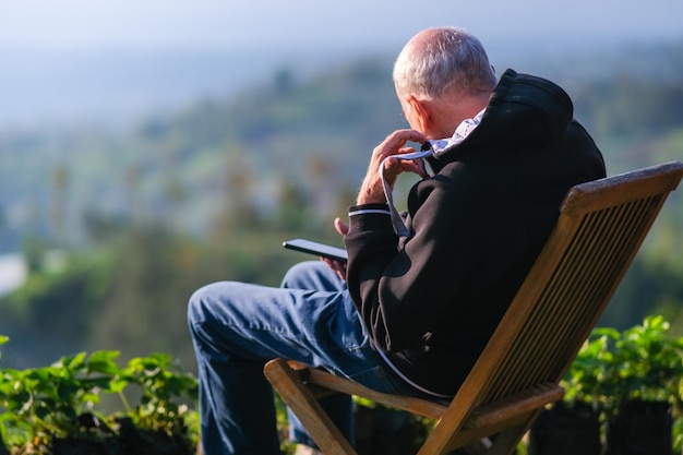 Photo man sitting on wooden chair and sunbathing on a hilltop