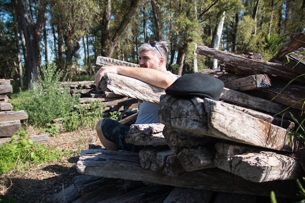 Человек, сидящий на деревянных бревнах в лесу