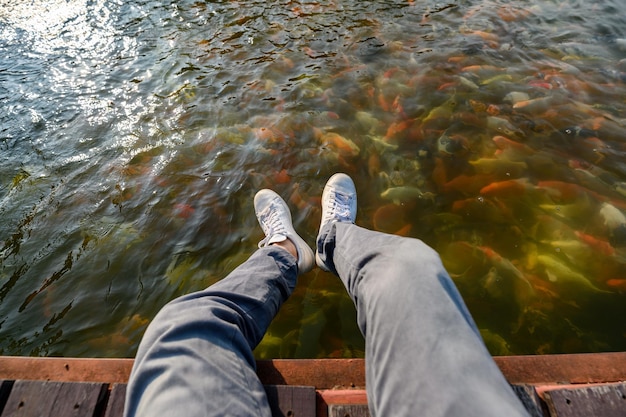 Man sitting on wooden patio with koi fish swimming in pond