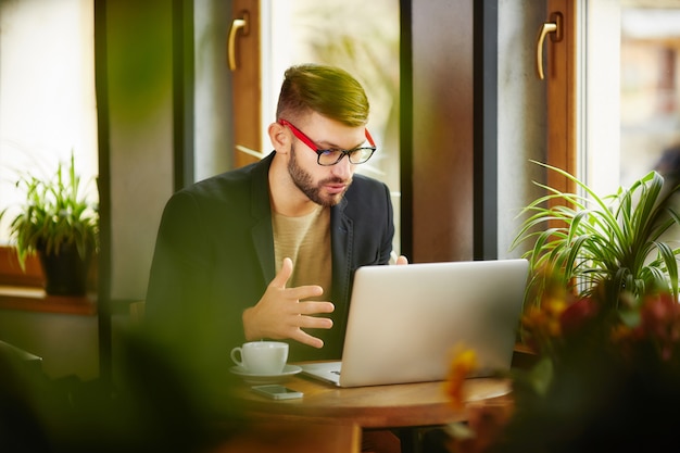 Foto uomo che si siede e lavora al computer portatile